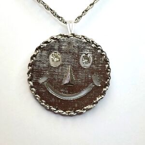 Gray smile face with dangle eye gems. Necklace and pin all in one